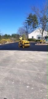 Man driving road roller over newly paved asphalt driveway