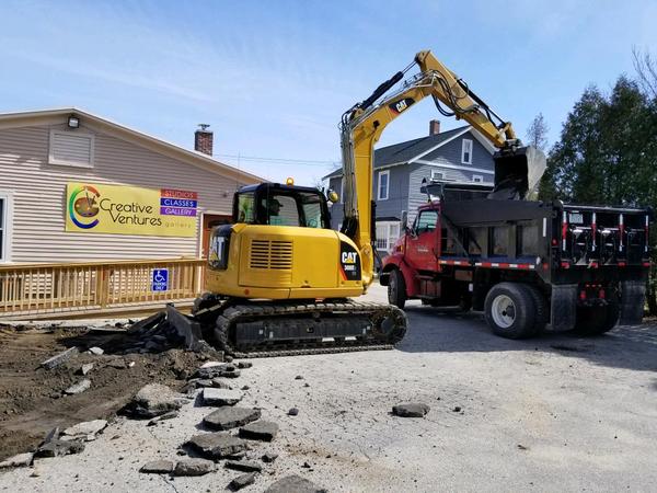 Skid steer loader dumping asphalt into dump truck